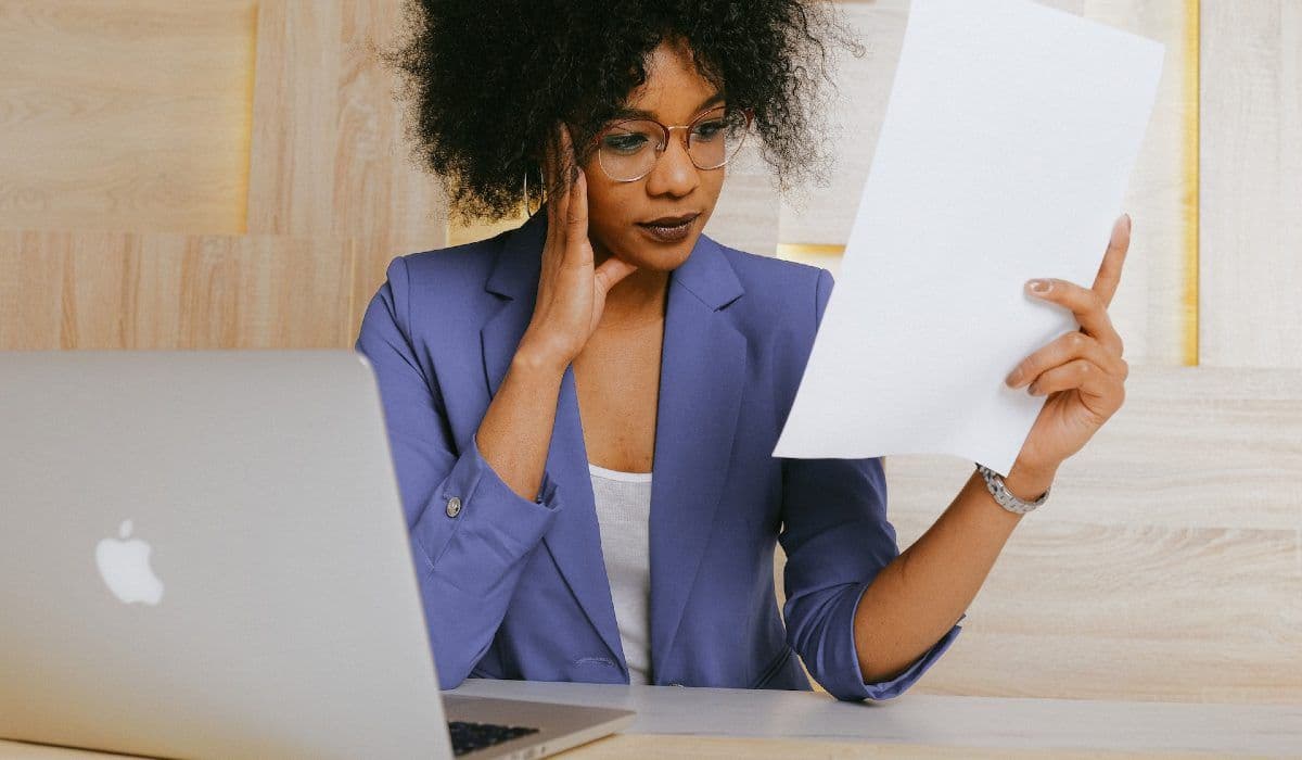Woman looks at a document near a computer